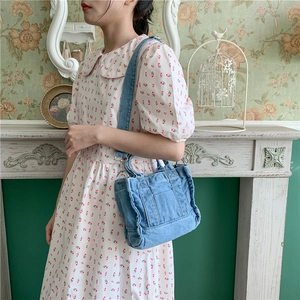 Close-up of blue denim tote bag with adjustable strap worn by model in vintage room