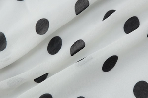 Macro shot of white chiffon fabric with black polka dots showing soft texture and drape