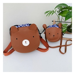 Detail of cute bear crossbody bag with brown lychee grain leather and checkered drawstring