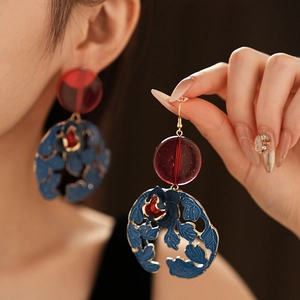 Detail of vintage style enamel earrings with blue floral patterns and red resin beads