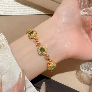 Detail of vintage 24K gold plated flower bracelet with emerald and ruby gemstones
