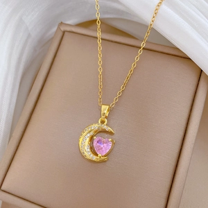 Detail of gold crescent moon and pink heart pendant necklace with shimmering crystals