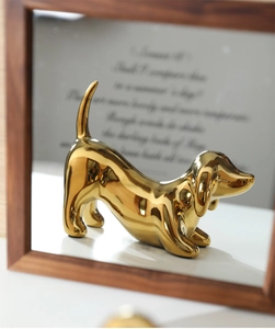 Detailed view of a golden ceramic dachshund sculpture with a shiny metallic finish