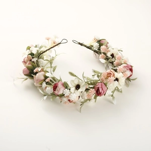 Dettaglio corona floreale da sposa con boccioli di rosa rosa e foglie verdi su bianco