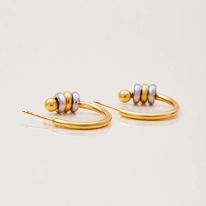 Detailed shot of two-tone gold and silver stackable rings on C-shaped hoop earrings