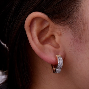 Close-up of heart-shaped gold hoop earring with pavé zircon stones on ear