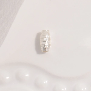 Macro detail of S925 sterling silver barrel bead featuring a geometric brick texture finish