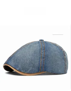 Detail of medium blue denim flat cap featuring orange stitching and brown leather brim trim