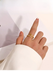 Detail of a golden snake-shaped ring with textured scales worn on a finger