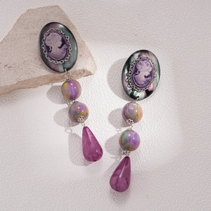 Macro detail of vintage purple resin cameo drop earrings with silver metallic hardware
