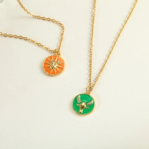 Close-up of gold titanium necklaces with orange lion and green bull enamel pendants