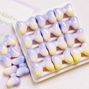 Purple and yellow gradient UV plated bow beads arranged on a clean white display tray