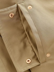 Macro shot of khaki twill fabric texture and polished light gold metal snap button closure
