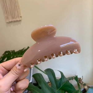 Close-up of a glossy nude pink hair claw clip for thick hair held in hand
