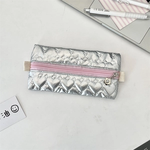 Silver quilted heart pencil case with flower zipper pull on a white desk setup