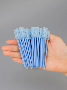 Close-up of a light blue disposable eyelash brush with spiral bristles and a smooth handle