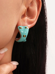 Close-up of model wearing C-shaped ocean-blue enamel hoop earrings with animal pattern
