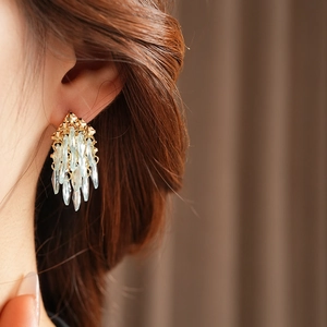 Vue détaillée de boucles d'oreilles géométriques dorées avec cristaux bleus sur un modèle