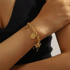 Gold plated stainless steel bracelet with cross and angel charms worn on wrist