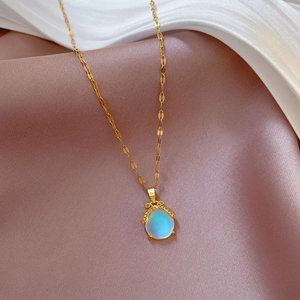 Detailed view of an oval aurora pendant on a gold chain over soft silk fabric texture