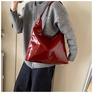 Dettaglio della borsa tote in pelle PU lucida rosso intenso portata a spalla da una modella