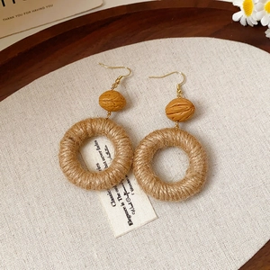 Detail view of Bohemian woven rattan earrings with wood beads on textured fabric
