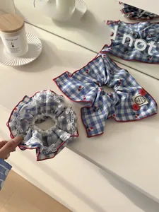 Detail of blue plaid headband with red cherry embroidery and handmade lace trim