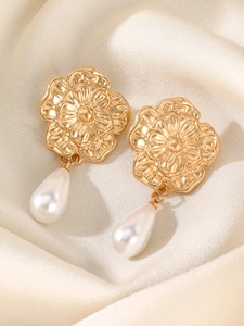 Macro detail of gold flower earrings with elegant white teardrop pearl drops