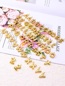 Macro shot of 26 golden metal bubble letters for DIY jewelry accessories and crafts