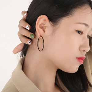 Close-up of minimalist black stainless steel hoop earring worn by a female model