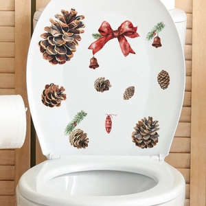 Christmas toilet lid sticker featuring red bow, pine cones, and bells on wood background