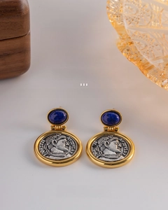 Detail of vintage coin earrings with blue gemstone and gold plated relief design