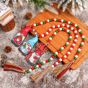 Christmas wooden bead garland with festive gnomes and tassels on a snowy wooden tray
