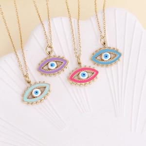 Detail of four golden evil eye necklaces with colorful enamel pendants on a shell tray