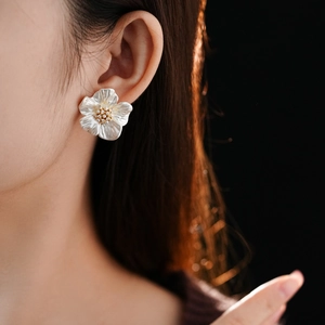 Detail of elegant white floral stud earring with pearl luster and golden pistil core