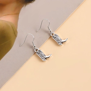 Gros plan de boucles d'oreilles bottes de cowboy en argent vintage avec gravures en métal