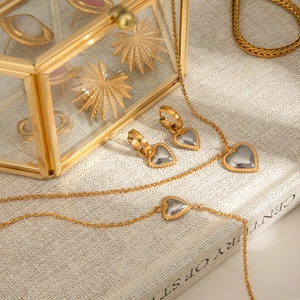 Detail of mixed-tone heart jewelry set including necklace and earrings on a book