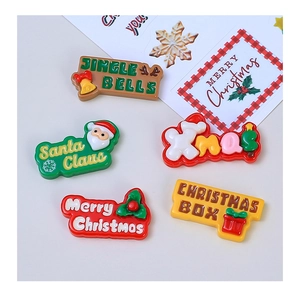 Makroaufnahme von fünf bunten Harz-Weihnachts-Accessoires mit Merry Christmas Schriftzug