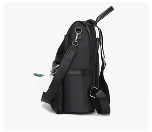 Side view of black nylon backpack featuring adjustable straps and a white fluffy charm