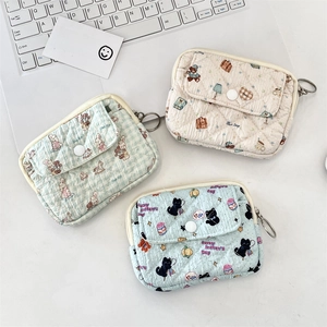 Three quilted floral card holders with flap pocket and zipper closure near laptop