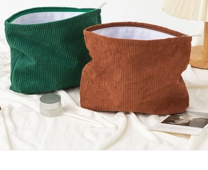 Detail of corduroy makeup bags in green and tan colors with textured fabric and metal zippers