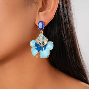 Detailed macro of vintage blue enamel flower earrings with sparkling zircons and gold plating
