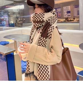 Close-up of brown and beige plaid knit scarf with tassels paired with a brown wool coat