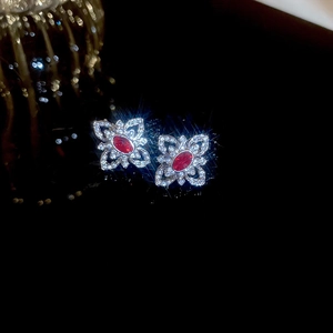 Macro shot of silver flower earrings with red gemstone and sparkling diamond accents
