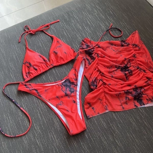 Detailed view of red marble print bikini top, high-cut bottom and mesh sarong skirt