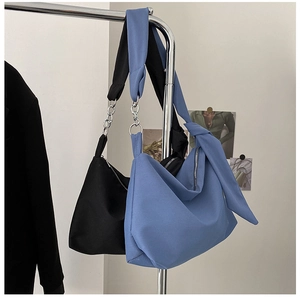 Detail of canvas tote bags with metal chain and knotted wide shoulder strap design