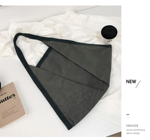 Detail of dark grey canvas tote bag with unique origami fold design and wide shoulder strap