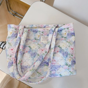 Detail of floral quilted cotton tote bag with French label on a white chair