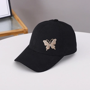 Close-up of black baseball cap featuring a detailed golden rhinestone butterfly ornament