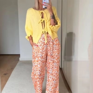 Sweet yellow tie-front knit cardigan with ruffles and orange printed wide-leg pants